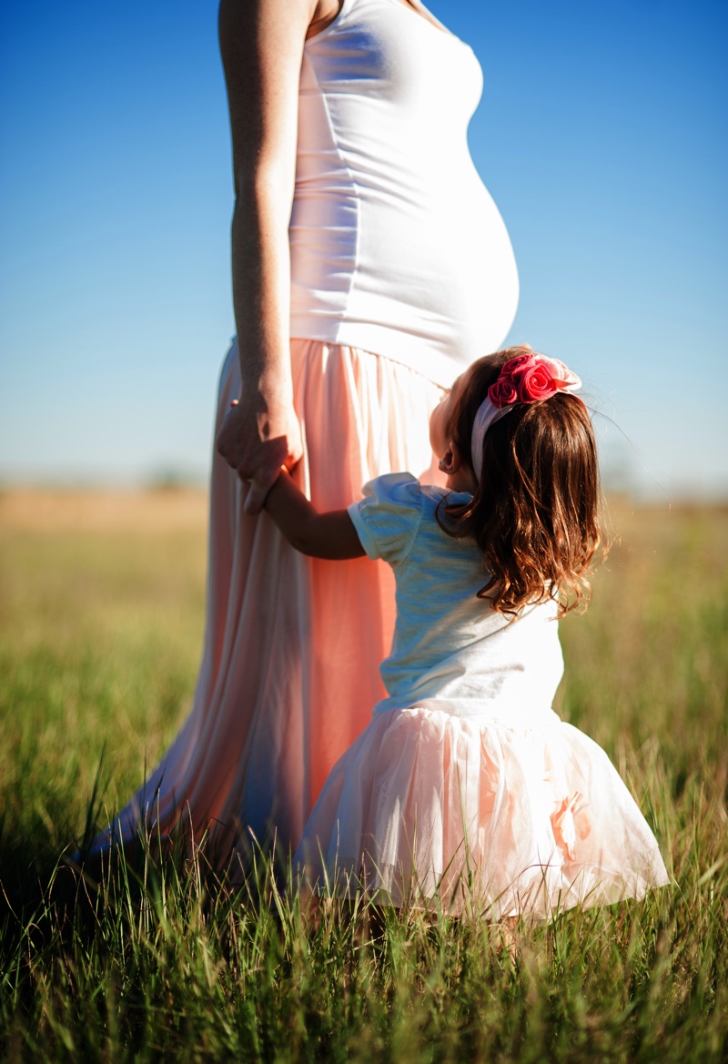 Pregnant woman in pink dress with little girl